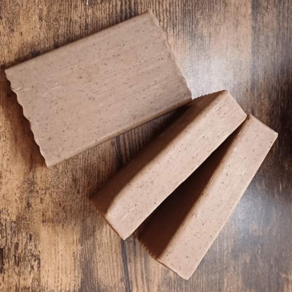 Three coffee scrub soaps are displaying straight an vertical on wood background.