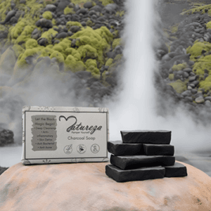 Natureza charcoal soap is on the big stone behind beautiful landscape like waterfall and log pine tree.