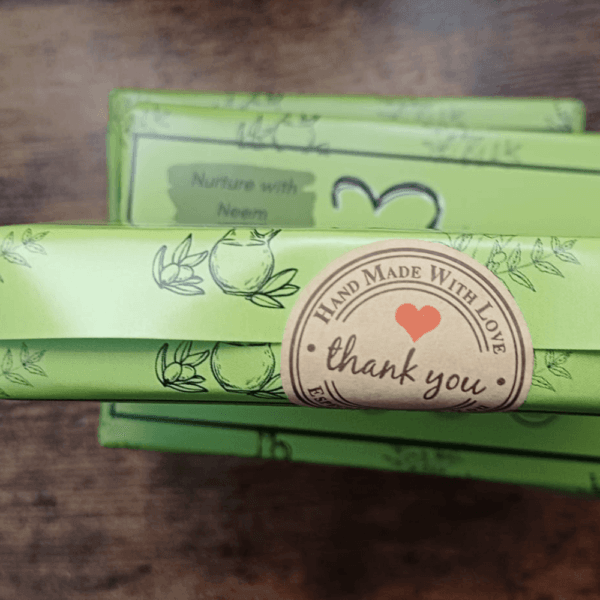 A stack of neem soap with thank you sticker on it, displaying on the plain surface.